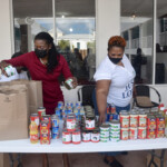 Wendy Butler, Vice President, Group & Health Benefits, Colina Insurance Limited (l) packs a food parcel while Recina Scully, Distribution Manager, The Bahamas Feeding Network (r) stocks the table.