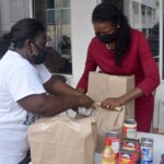 Wendy Butler, Vice President, Group & Health Benefits, Colina Insurance Limited tapes a completed food parcel with the assistance of a BFN volunteer.