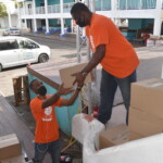(l to r): Rashad Lynes, Provider Relations Representative and O'Neil Stubbs, Senior Group Account Representative, Group & Health Benefits, Colina Insurance Limited lifting boxes with supplies for food parcels. AHVIA J. CAMPBELL