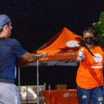 Christina Minnis, Group Billing Administrator at Colina, handing water to a participant in the ‘Paint Da Streets Pink’ Fun, Run, Walk.