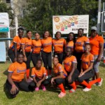 Colina Crushers girls’ softball team players with Maxine Seymour, Director of Corporate Communications at their team sponsor, Colina. (missing from photo: Stephen “Bishop” Beneby, head coach)