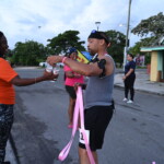 Maqueria Rolle, Customer Service Representative at Colina, handing water to a participant in the ‘Paint Da Streets Pink’ Fun, Run, Walk.