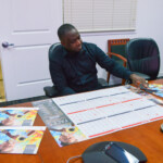 Allan admires the desk, wall, and wall posters of the calendars with his artwork.