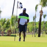 Ramon walks to the hole with a smile after sinking his putt, ready to retrieve his ball.