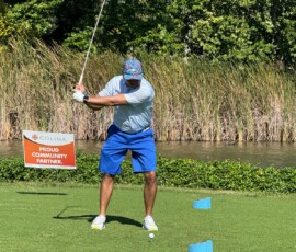 A golfer tees off at the Colina-sponsored hole, taking a swing with concentration.