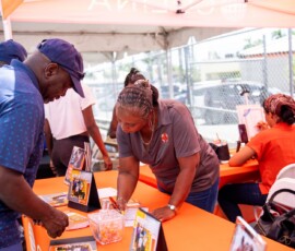 Colina sales representatives Charmaine Fernander assists an attendee during the Guardian Media Group’s back-to-school giveaway.